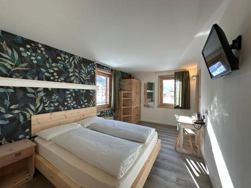 a bedroom with a bed and a tv on a wall at Garni La Casetta in Livigno