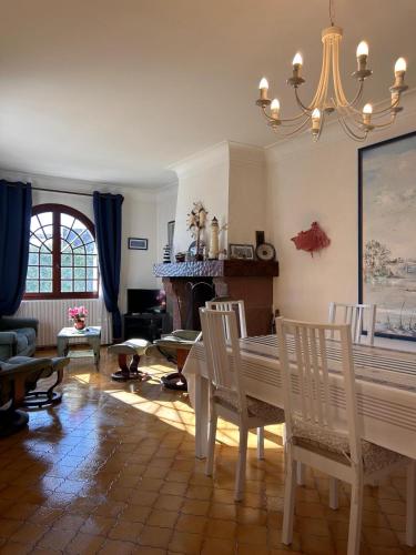 - un salon avec une table, des chaises et un lustre dans l'établissement Charmante maison avec jardin proche plage, à Gujan-Mestras