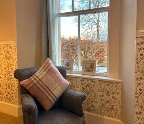 a chair sitting in front of a window with two picture frames at Estate Of Ord in Muir of Ord