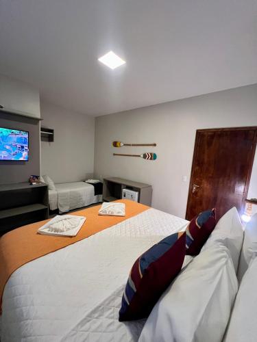 a bedroom with a large bed and a television at POUSADA ATALAIA NORONHA in Fernando de Noronha