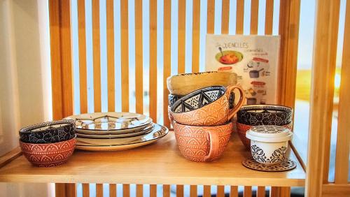 a shelf with cups and plates on a table at Proche Hôpital LyonSud Metro B Calme et WiFi in Pierre-Bénite