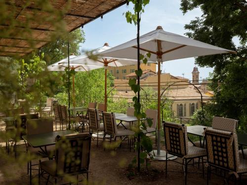 een groep tafels en stoelen onder een parasol bij Hôtel du Couvent, a Luxury Collection Hotel, Nice in Nice