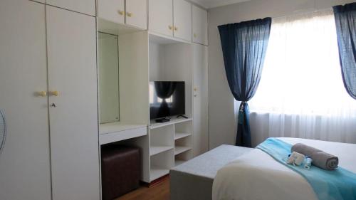 a bedroom with a bed and a tv and a window at Kombi Cove Blaauwberg in Cape Town