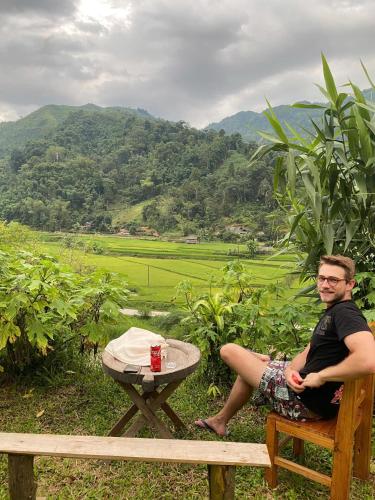a man sitting on a bench next to a table at Tay Eco House in Ha Giang