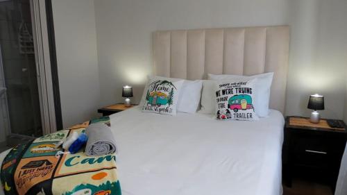 a bedroom with a white bed with pillows on it at Kombi Cove Blaauwberg in Cape Town