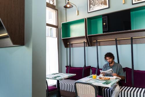 a man sitting at a table with a plate of food at Room Mate Luca, Florence in Florence