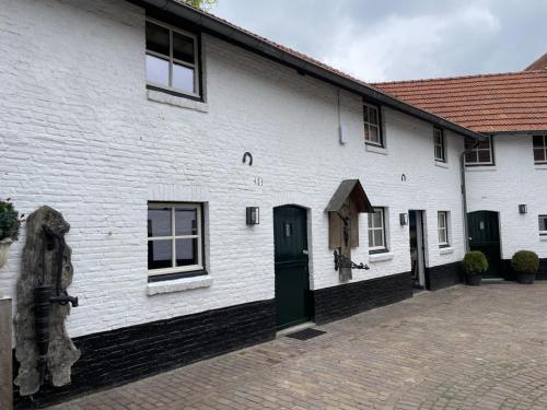 a white building with a green door and windows at Sfeervolle 4 persoons cottage vlakbij Valkenburg in Voerendaal