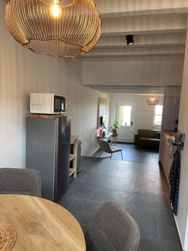 a kitchen and living room with a table and a microwave at Gezellige cottage bij Valkenburg in Voerendaal