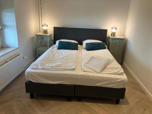 a bed in a room with two nightstandiatesiatesiatesiatesiatesiatesiates at Authentiek 4 persoonshuisje vlakbij Valkenburg in Voerendaal