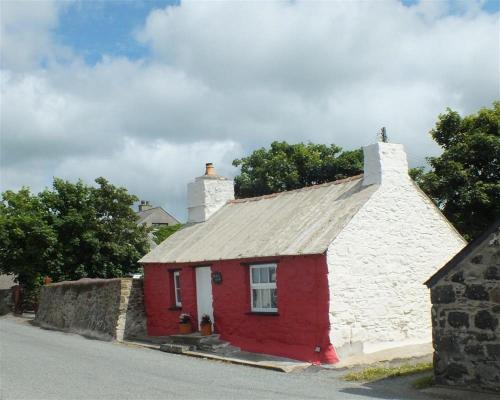 a red and white house with a stone wall at Bwthyn Alarch in Haverfordwest