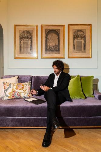 a man in a suit sitting on a purple couch at Room Mate Collection Isabella, Florence in Florence