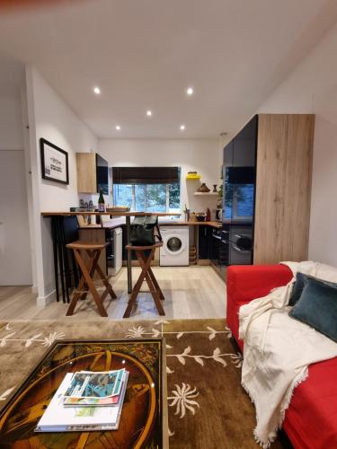 un salon avec un canapé rouge et une cuisine dans l'établissement SOLEIL MARIN CENTRE ST-BRIAC chaleureux, à 2 min de la plage, à Saint-Briac-sur-Mer