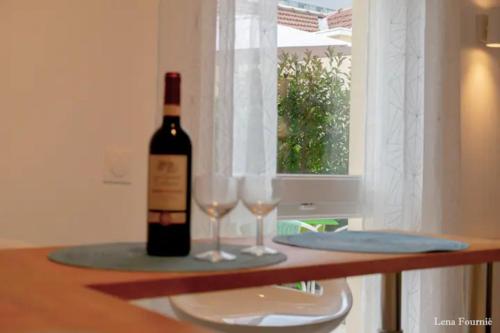 une bouteille de vin posée sur une table avec deux verres dans l'établissement Maison chaleureuse jacuzzi, climatisation et parking payants, à Bagneux