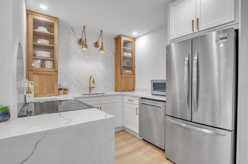 une cuisine avec des armoires blanches et un réfrigérateur en acier inoxydable dans l'établissement Renovated Ski In Out Condo King Bed Patio Grill, à Ellicottville