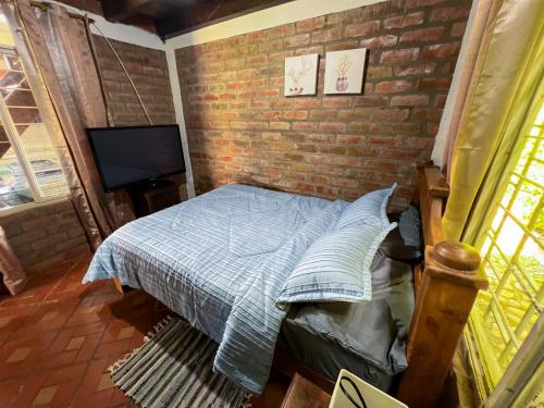 a bedroom with a bed and a brick wall at Finca Cabaña con piscina cerca al Lago Calima in Calima