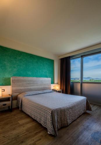 a bedroom with a large bed and a large window at Hotel Galilei in Pisa