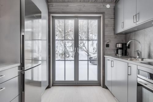 a kitchen with white cabinets and a sliding glass door at Bastuvallen - Ramundberget in Bruksvallarna