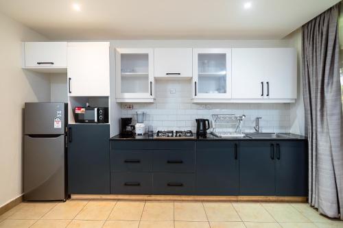 a kitchen with white cabinets and a blue refrigerator at Harry's Kisumu Oasis in Kisumu