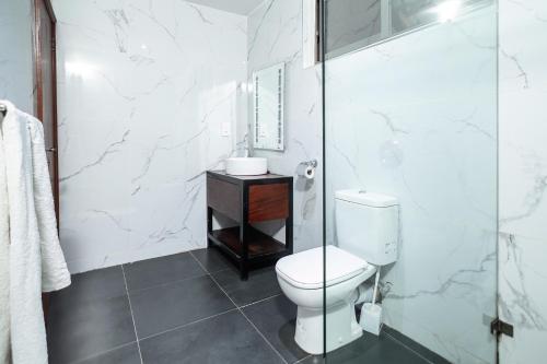 a bathroom with a toilet and a glass shower at Harry's Kisumu Oasis in Kisumu