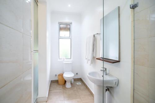 a white bathroom with a toilet and a sink at Harry's Kisumu Oasis in Kisumu