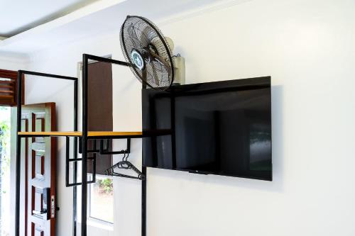 a flat screen tv hanging on a wall with a fan at Harry's Kisumu Oasis in Kisumu
