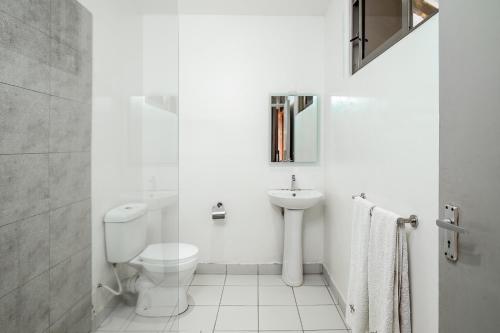 a white bathroom with a toilet and a sink at Harry's Kisumu Oasis in Kisumu