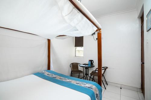 a bedroom with a bed and a small table at Harry's Kisumu Oasis in Kisumu
