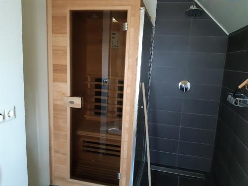 a shower with a glass door in a bathroom at Gastenverblijf Lheederhof Lodge 3 in Dwingeloo