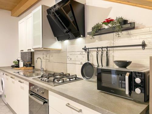 a kitchen with a stove and a microwave at Thiago Home-Elegant Mansarda Santa Giulia Square in Turin