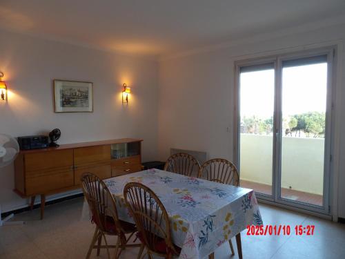 une salle à manger avec une table et des chaises et une fenêtre dans l'établissement St Cyprien Appart lumineux face mer, à Saint-Cyprien