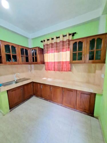 an empty kitchen with wooden cabinets and a sink at Monara Villa in Hikkaduwa