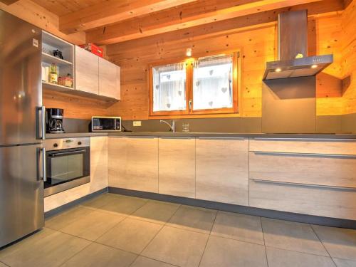 - une cuisine avec des murs en bois et des appareils en acier inoxydable dans l'établissement Chalet Moderne 91m² à Morzine, Proche Navettes et Remontées, Quartier Calme - FR-1-524-22, à Morzine