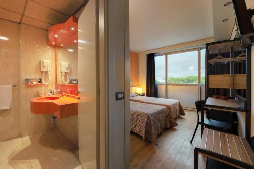 a hotel room with a bed and a bathroom with a sink at Hotel Galilei in Pisa