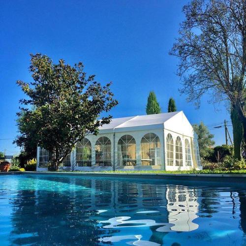Une grande serre blanche avec de l'eau devant elle dans l'établissement Bastide des Calades, à Lançon-Provence