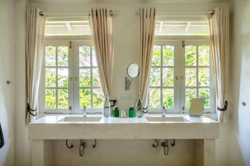 a bathroom with two sinks and two windows at The Sun House in Galle