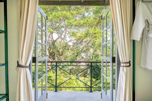 an open door to a balcony with trees at The Sun House in Galle