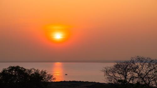 a sunset over the water with the sun in the sky at Musungwa Safari Lodge in Shanjungu