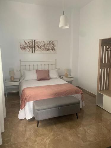 a bedroom with a large bed with a gray ottoman at Apartamento Cerezo in Carmona