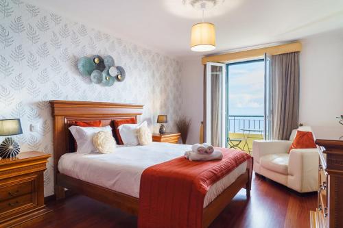 a bedroom with a bed and a chair and a window at GuestReady - Breathtaking seaview in Caniço in Caniço
