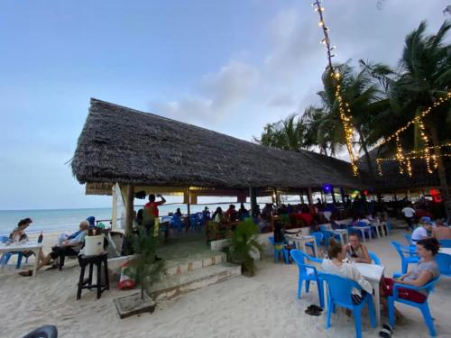 a group of people sitting at tables on the beach at The New Big Tree Beach Resort in Mombasa