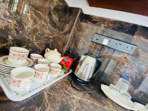 a shelf with cups and plates and a coffee maker at Coco Bay Villa in Galle
