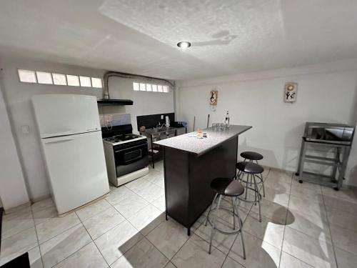 a kitchen with a white refrigerator and a counter with stools at Suite #1B Cerca de autopista Mex-Qro. in Cuautitlán Izcalli