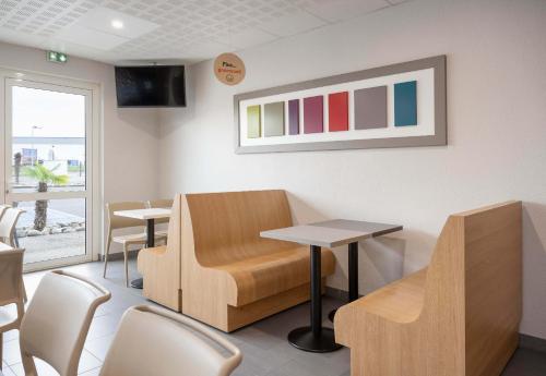 a waiting room with tables and chairs and a window at B&B HOTEL Mont-de-Marsan in Saint-Avit