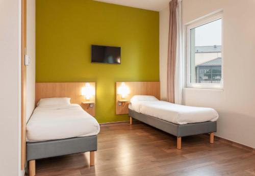 two beds in a room with a green wall at B&B HOTEL Mont-de-Marsan in Saint-Avit