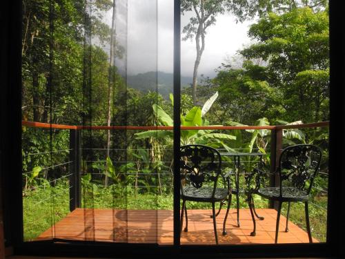 a balcony with a table and chairs and a window at Mogambo Ecolodge in Viotá