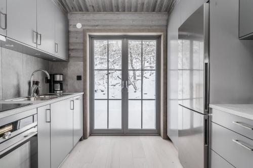 a kitchen with a large glass door to a window at Bastuvallen - Ramundberget in Bruksvallarna