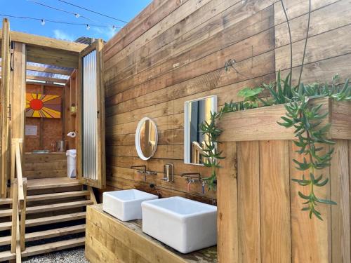 a bathroom with two sinks and a wooden wall at Greenfinch Lakeside Bell Tent Basic with Airbeds Only in Saint Columb Major