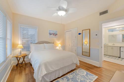 a white bedroom with a bed and a mirror at Sea of Cedar Key in Cedar Key