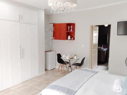 SERENE Guest House في ميدراند: غرفة نوم بها سرير وطاولة وكراسي