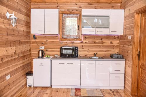 a kitchen with white cabinets and a refrigerator at Ostrog Wood House in Železnička Stanica Dabovići